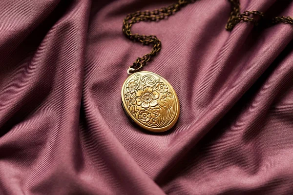 Mor kumaş arka planda büyükannenin bronz madalyonu.