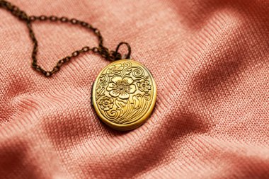 old vintage grandma's bronze locket on a pink fabric texture