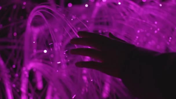 A hand brushes past fiber optics — Stock Video