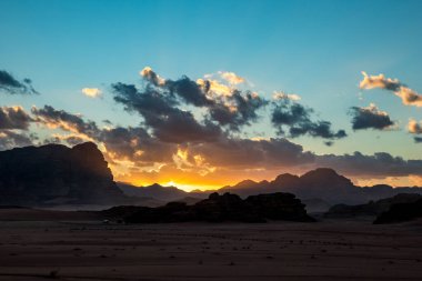 Ürdün Krallığı, Wadi Rum Çölü, etkileyici günbatımı gökyüzü ve çölün üzerindeki aydınlık karanlık ve gölgeler. Güzel seyahat fotoğrafçılığı. Safaride güzel bir çöl keşfedilebilir. Renkli resim