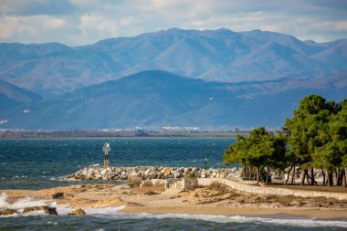 Küçük göktaşı istasyonu, çam ağaçları ve uçan martıları olan manzara sahili. Sonbaharın sonlarında Kuzey Yunanistan 'ın Xanthi bölgesindeki Fanari köyü yakınlarında inanılmaz güneşli bir gün. Arka planda görkemli dağ