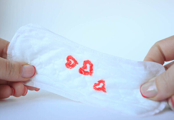 женская гигиеническая прокладка на мягком бежевом фоне, менструальная концепция
