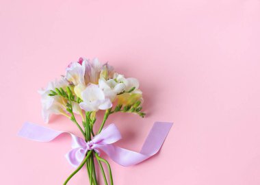 Bahar çiçeklerinden oluşan bir buket, bir pastel gölgenin pembe arka planında yatar. Bayramlık bir minimalizm, düzlük.