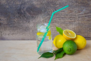 Taze sıkılmış limonlu bir içki şişesi ve hafif bir arka planda duran bir pipet.