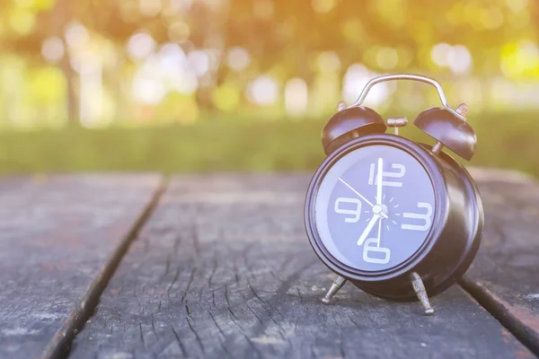 Stock Photo Concepto horario de verano. Reloj despertador sobre mesa de madera sobre fondo de campo —  Fotos de Stock