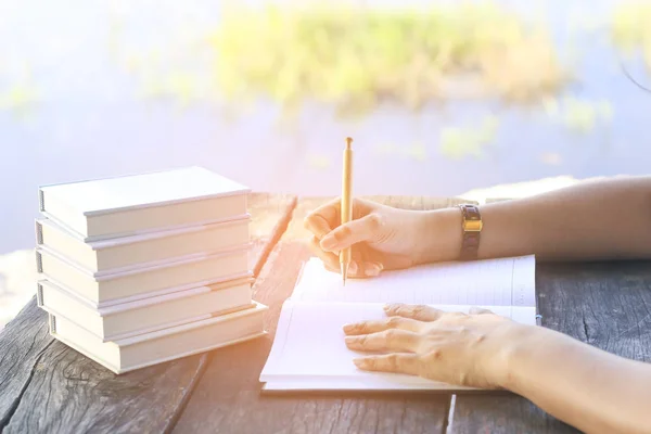 Archivfoto Frau rechts schreibt Tagebuch auf kleinem Notizbuch im Außenbereich mit Morgenszene — Stockfoto