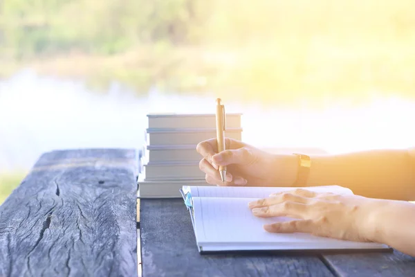 Skladem Foto žena pravou rukou psaní deníku na malý notebook na venkovní prostor s ranní scéna — Stock fotografie