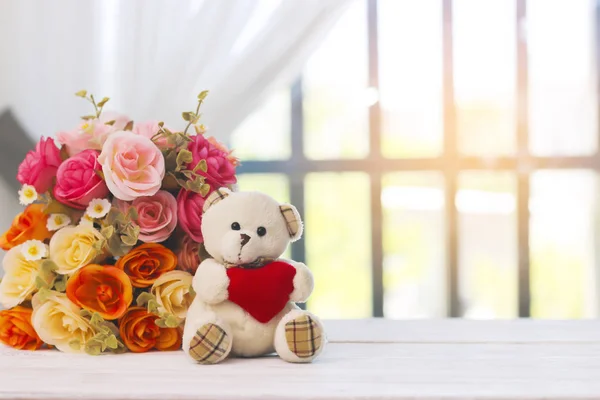 Stock Photo Teddy bear sitting on window with beautiful Faked flowers bouquet. — Stock Photo, Image