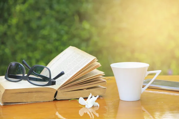 Stock foto närbild glasögon på bok och kaffe på bordet på morgonen — Stockfoto
