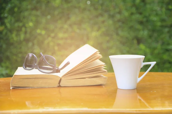 Archivbild Großaufnahme Gläser auf Buch und Kaffee am Morgen auf dem Tisch — Stockfoto