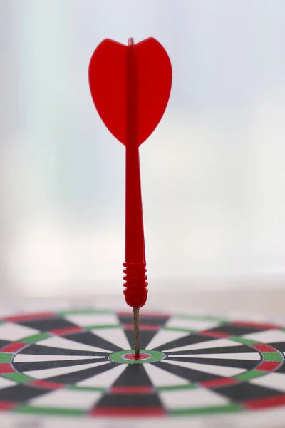 Stock Photo Dart in bulls eye of dartboard with shallow depth of field concept for hitting target.