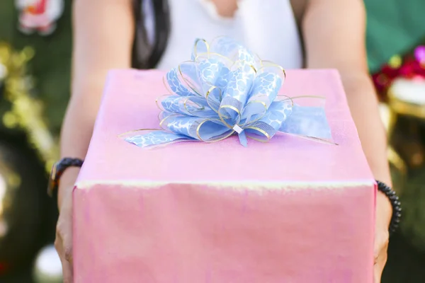 Stock Photo Close up shot of female hands holding a big gift wrapped with blue ribbon. — Stock Photo, Image