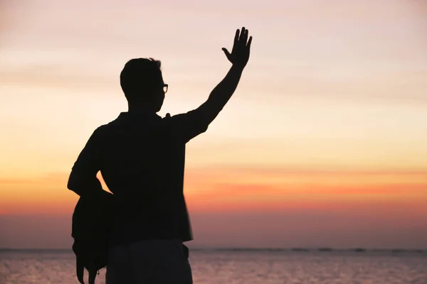 Stock de fotos hombre silueta mirando hacia fuera en la roca en el fondo de la puesta del sol multicolor — Foto de Stock