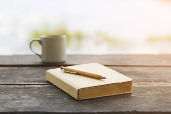 Склад Фото коричневая записная книжка с карандашом и чашкой кофе на гранж деревянный стол — стоковое фото