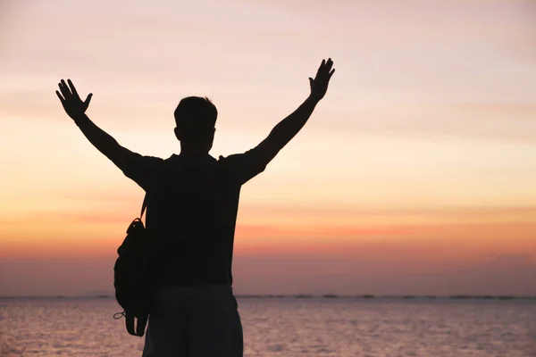 Voorraad foto man silhouet uitkijkend op de rots bij multi-gekleurde zonsondergang achtergrond — Stockfoto