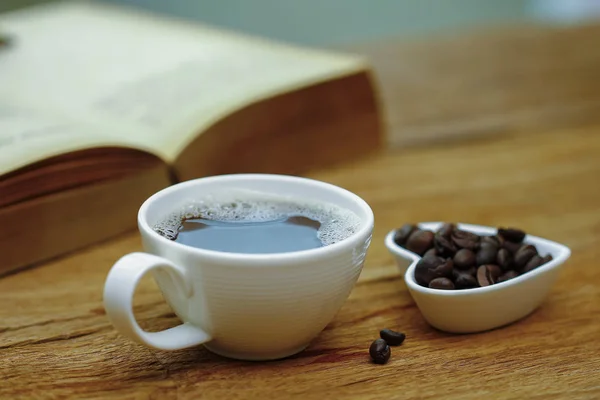 Foto de stock - Taza de café y libro sobre mesa de madera - vintage (retro ) —  Fotos de Stock