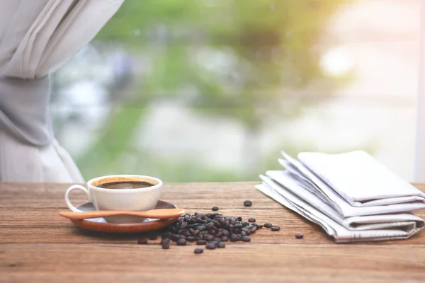 Tasse de café avec faisceau de café et journaux, près de la fenêtre — Photo