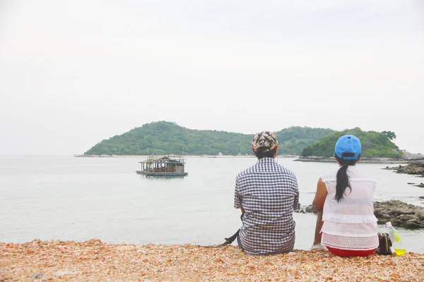Archivbild - junges Paar sitzt auf einer Klippe und blickt aufs Meer — Stockfoto