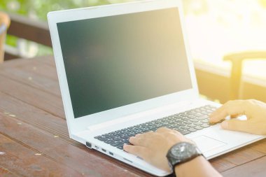 Stok fotoğraf yakın düşük açılı görünümü ile tahta masada oturan bir dizüstü bilgisayar üzerinde çalışan bir adam kadar doğa arka plan bulanıklık