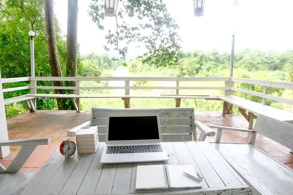 Varastossa kuva Kannettava tietokone Tyhjä näyttö päälle luonnon puinen pöytä ja retro valkoinen ja villieläinten tausta. Graafisen suunnittelun näyttö — kuvapankkivalokuva