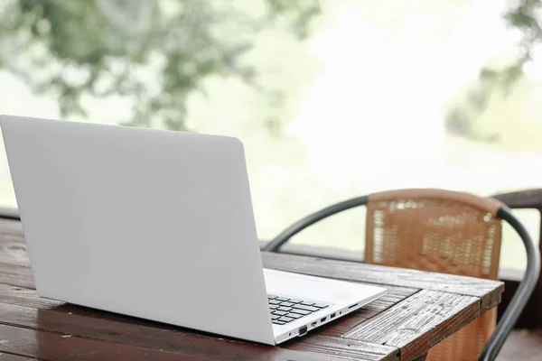 Zdjęcie stockowe komputer laptop z pusty ekran wstecz na drewnianym stole z tło zielony natura ogród — Zdjęcie stockowe