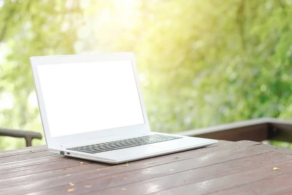 Zdjęcie stockowe komputer laptop z pusty ekran wstecz na drewnianym stole z tło zielony natura ogród — Zdjęcie stockowe