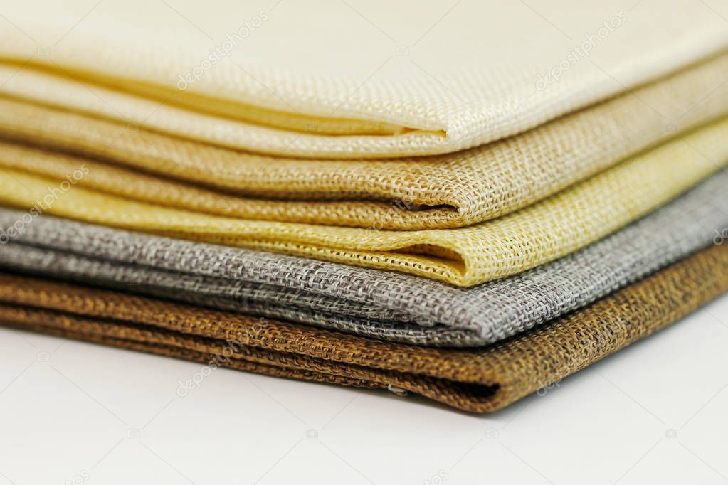 A pile of four folded dull-colored cotton fabric by a stalk of d