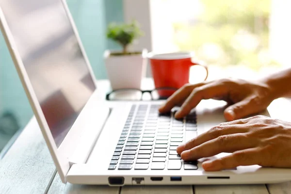 Männerhände mit Laptop mit leerem Bildschirm auf Schreibtisch in der Wohnung — Stockfoto