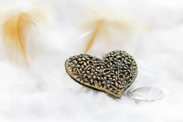 Black silver heart pendant on white background with feathers — Stock Photo, Image