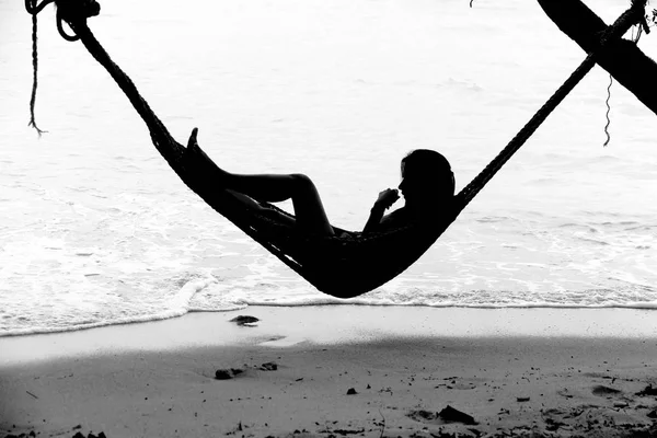 A black and white woman on a hammock in the tropical  over the s