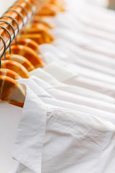 Faltenfreie weiße Hemden, die am Regal in einer Reihe hängen, selektiver Fokus — Stockfoto