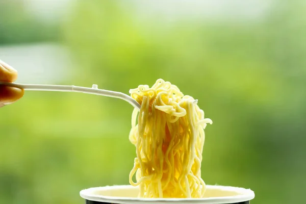 Instant noodle i skål med plast gaffel på grön bakgrund — Stockfoto