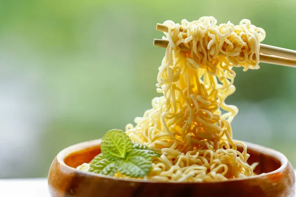 Instant noodle in wooden bowl with bamboo chopstick on green bac — Stock Photo, Image