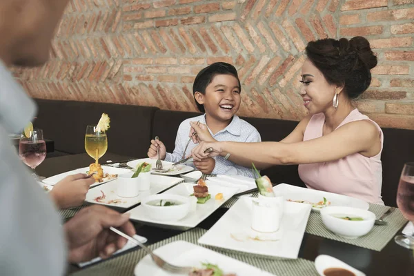 La madre che aiuta il figlio a tagliare il cibo in piatto — Foto Stock