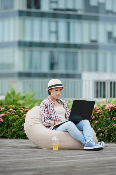 Vrouw zitten in de poef en die op laptop werkt — Stockfoto