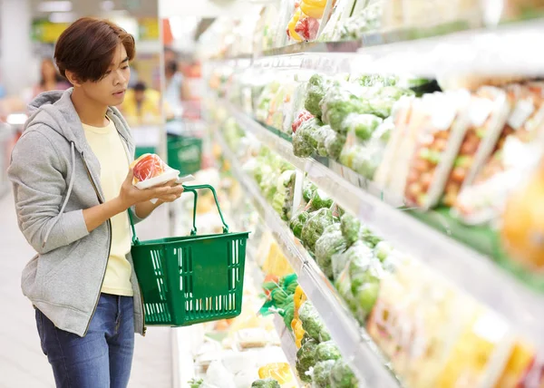 Homme choisissant des légumes au supermarché — Photo