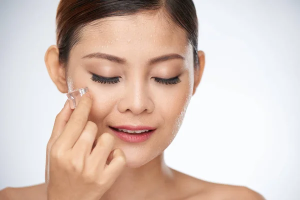 Frau reibt Gesicht mit Eiswürfeln — Stockfoto