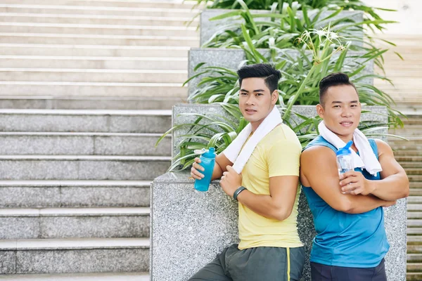 Sportsmen drinking water after outdoor training — Stock Photo, Image