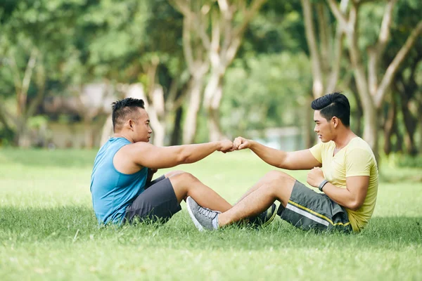 Desportistas tocando punhos ao fazer sit-ups — Fotografia de Stock