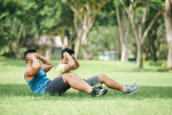 芝生の上の腹筋を行う男性 — ストック写真