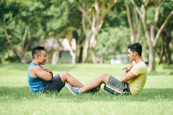 Athletes helping each other to do sit-ups — Stock Photo, Image