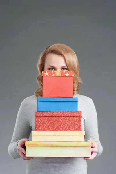 Woman hiding behind stack of presents — Stock Photo, Image