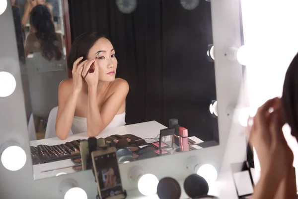 Девушка делает макияж перед зеркалом — стоковое фото