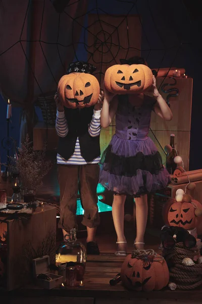 Children hiding faces behind pumpkins — Stock Photo, Image