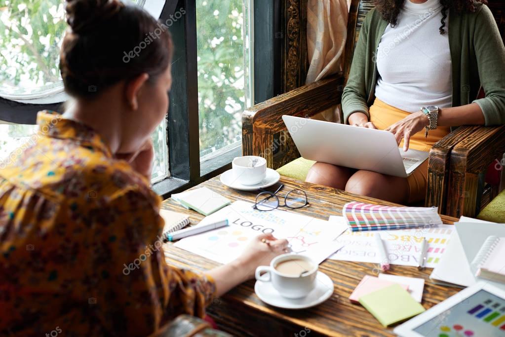 Female web designers working in cafe