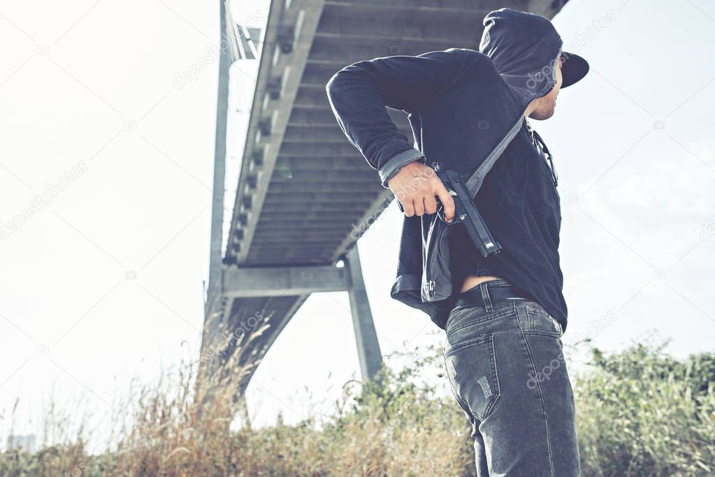 Gangster putting pistol into back pocket