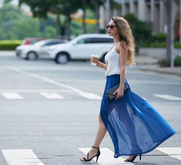 Femme en jupe flatteuse traversant la route — Photo