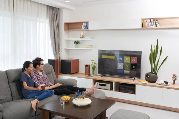 Casal sentado no sofá e assistindo tv — Fotografia de Stock