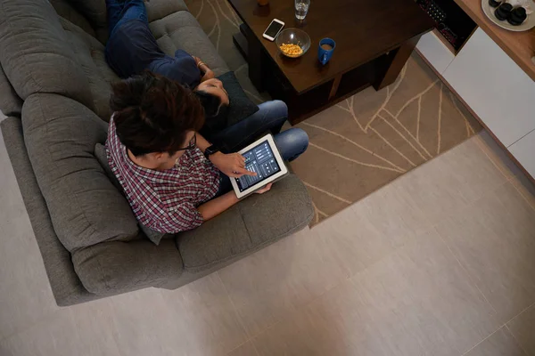 Pár sedí na pohovce a pomocí digitálního tabletu — Stock fotografie