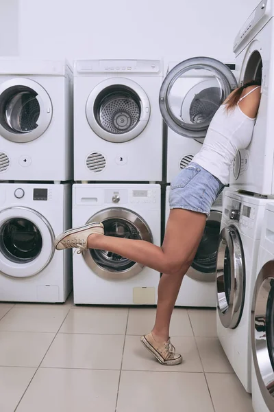 Vrouw op zoek naar wasmachine — Stockfoto